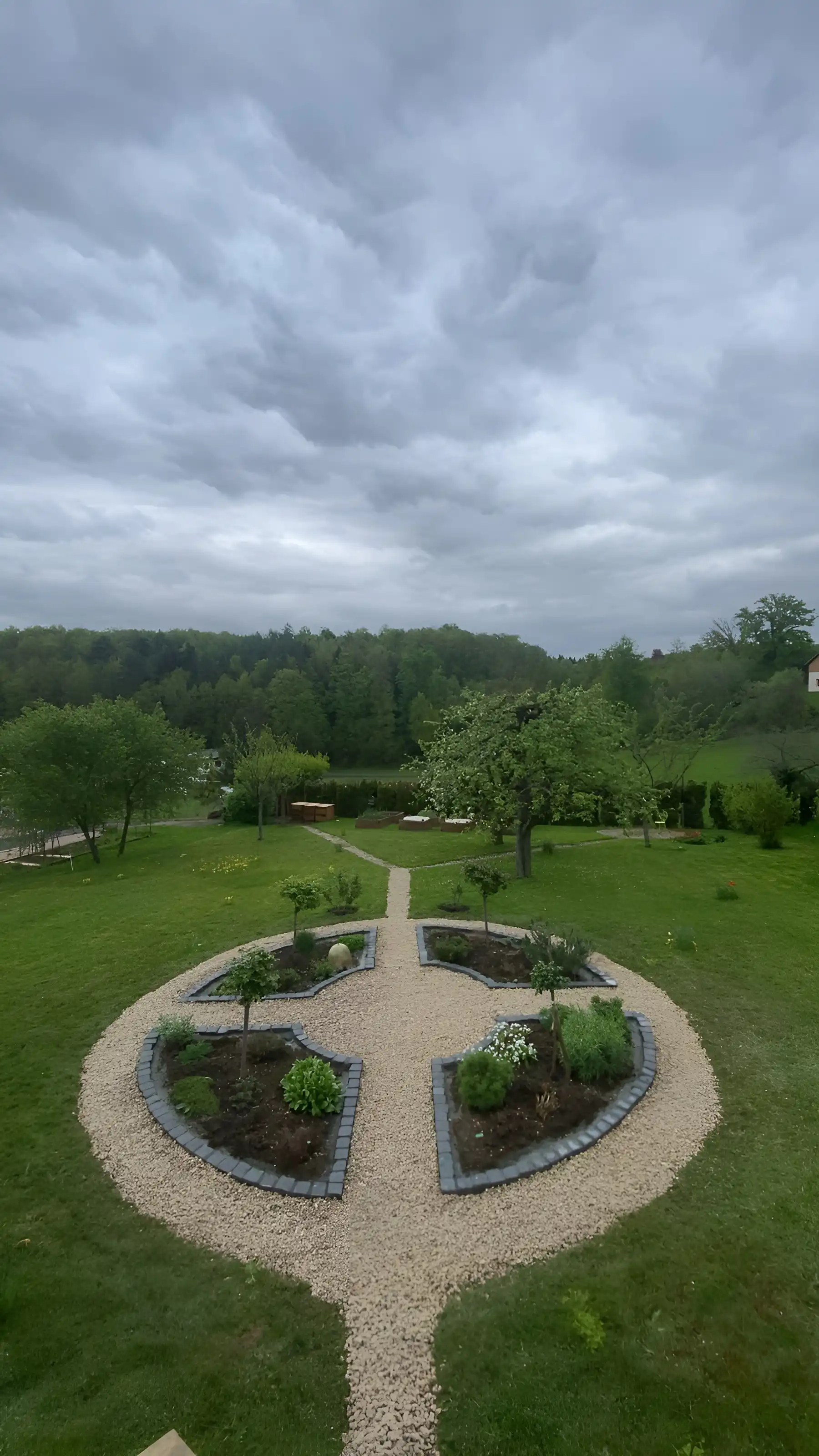 Le même jardin vu d'en haut : un cercle de gravier divisé en quatre quartiers plantés, bordés de pavés