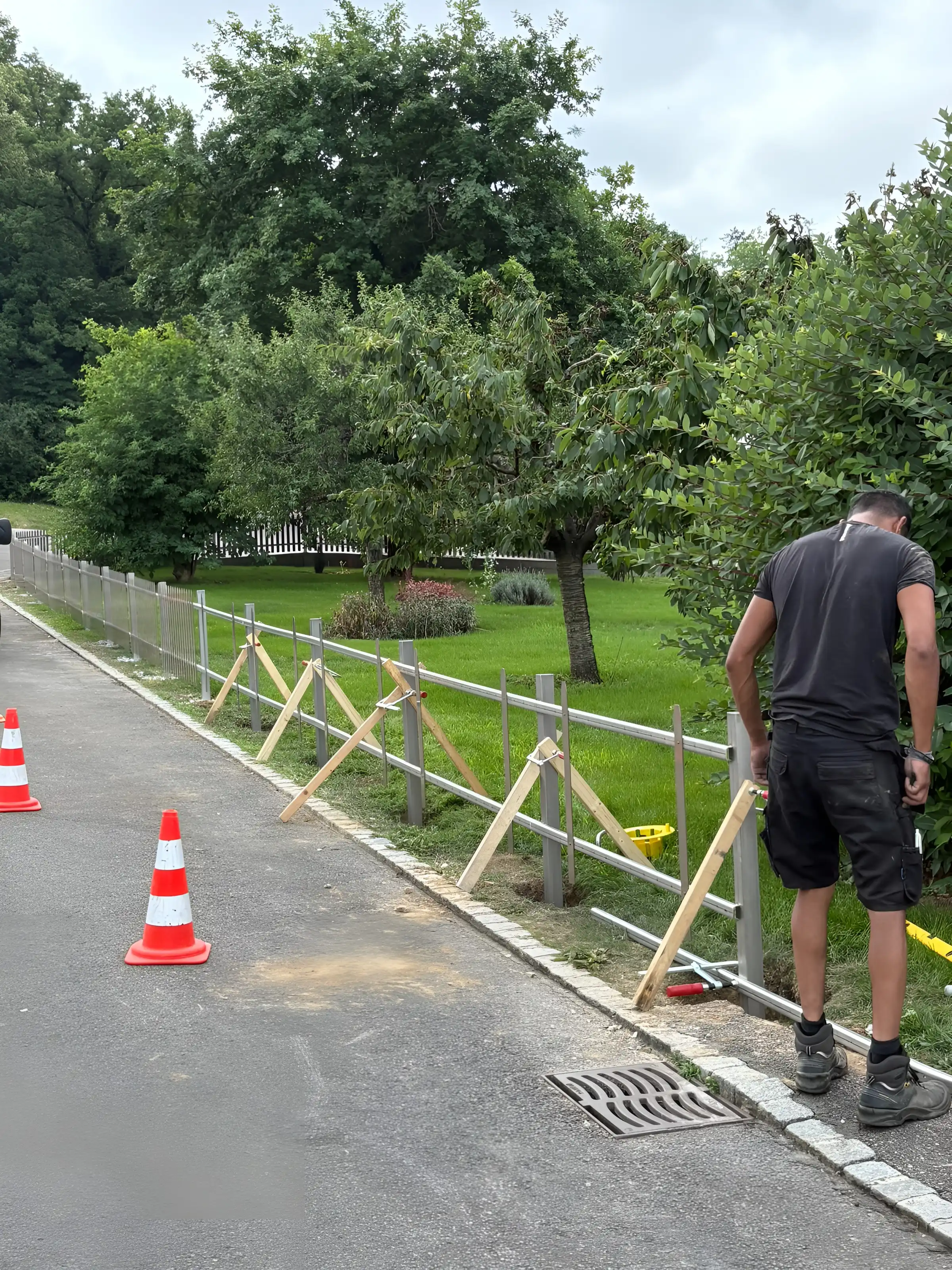 Pose d'une clôture en bois le long d'une route, cônes de chantier